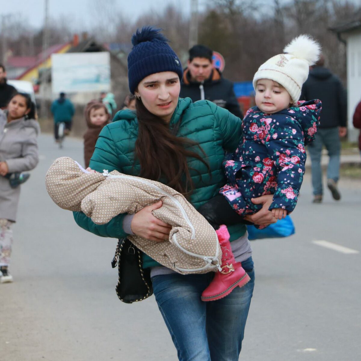 A young Ukrainian mother carries her three-month-old baby and her three-year-old toddler across the Tiszabecs border crossing into Hungary after she fled Ukraine leaving her husband behind. On arrival, Ukrainians and other nationalities are screened and registered. They are guided to assembly points where they can apply for asylum and are given temporary documentation. ; Russia launched its military offensive in Ukraine on 24 February 2022. By 27 February, hundreds of thousands of people had fled to safety inside Ukraine or neighbouring countries. The largest numbers headed west into Poland, with others making for Hungary, Moldova, Romania and beyond.