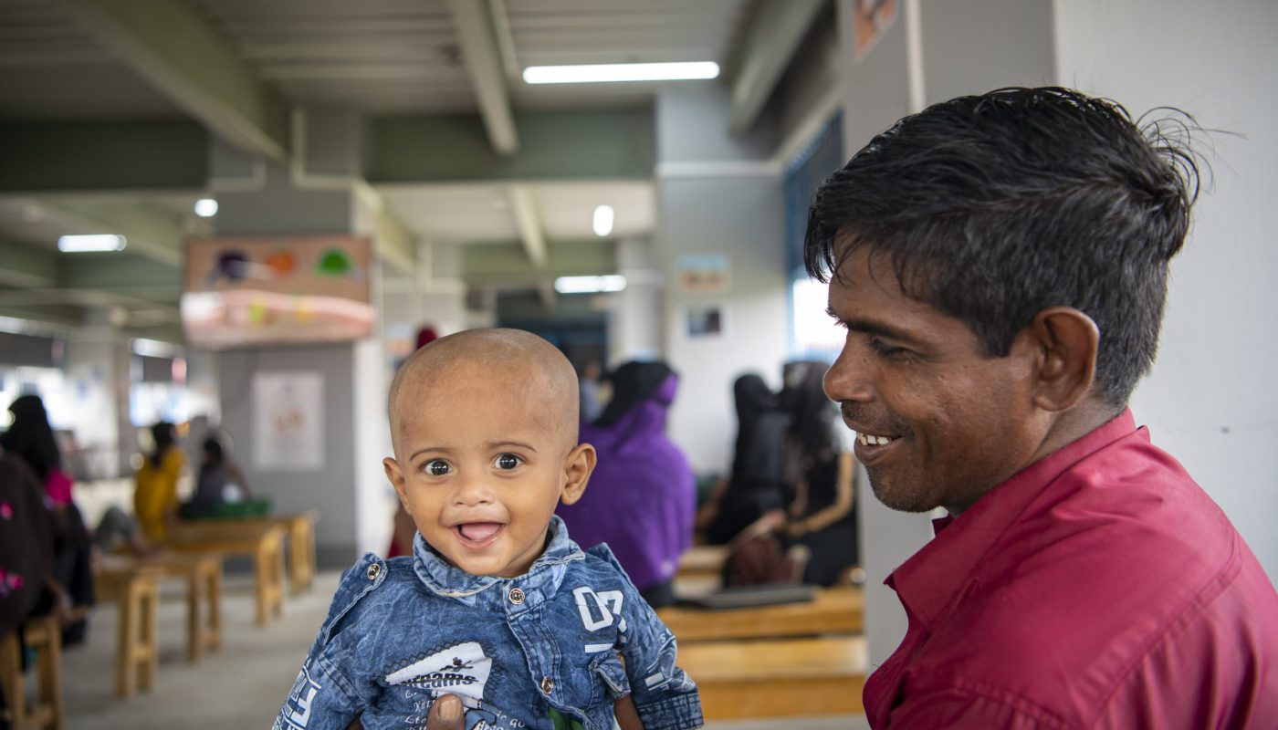Abdul Amin brings his son to the Bhasan Char registration centre, which is providing verification services to the 28,000 Rohingya refugees relocated from the Kutupalong and Teknaf refugee settlements of Cox's Bazar. High Commissioner Filippo Grandi is visiting the centre, which is ready to support 100,000 refugees before December 2022 and will help with registration of births, deaths, marriages, divorces and changes in family composition on an ongoing basis. ; Bangladesh has hosted Rohingya refugees for the past 30 years, as the community has fled waves of persecution in Myanmar since 1992. Today it is host to more than one million refugees, and more than 742,000 of those have fled violence in Myanmar since 25 August 2017.  Some 28,000 refugees have been relocated to Bhasan Char from the Kutupalong and Teknaf settlements of Cox's Bazar. UN agencies, under the leadership of UNHCR, have assessed the needs of these refugees, including registration, protection, health, nutrition, and logistics requirements, and have begun establishing community protection networks and transport, storage and distribution systems on the island.